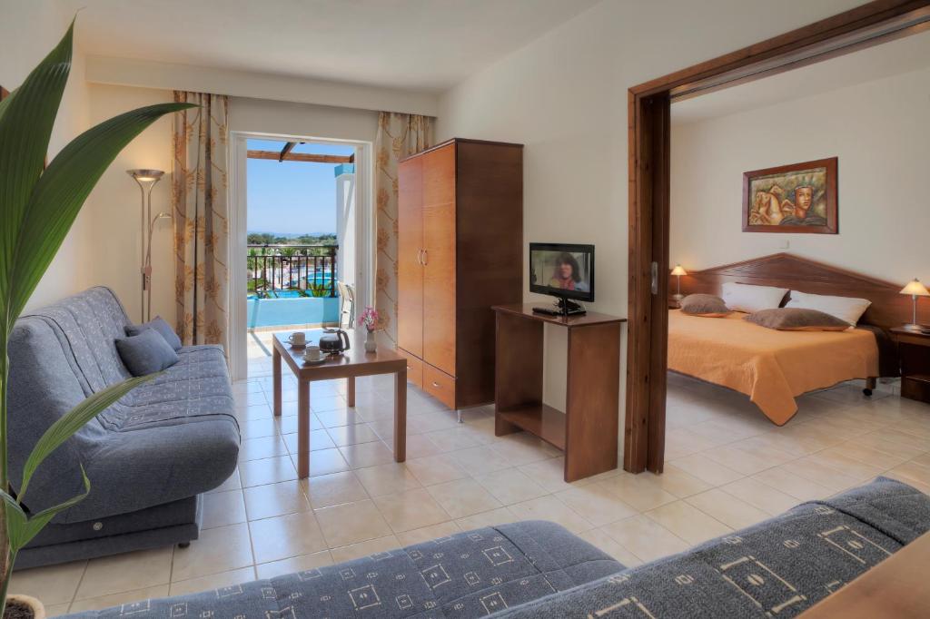 a bedroom with a bed and a living room with a couch at Corali Hotel in Tigaki