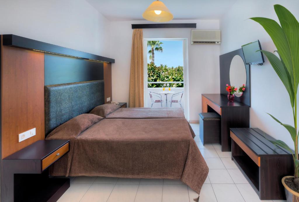 a bedroom with a large bed and a balcony at Corali Hotel in Tigaki