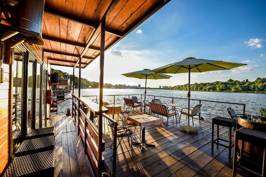 a wooden deck with tables and chairs and umbrellas at San Art Floating Hostel & Apartments in Belgrade