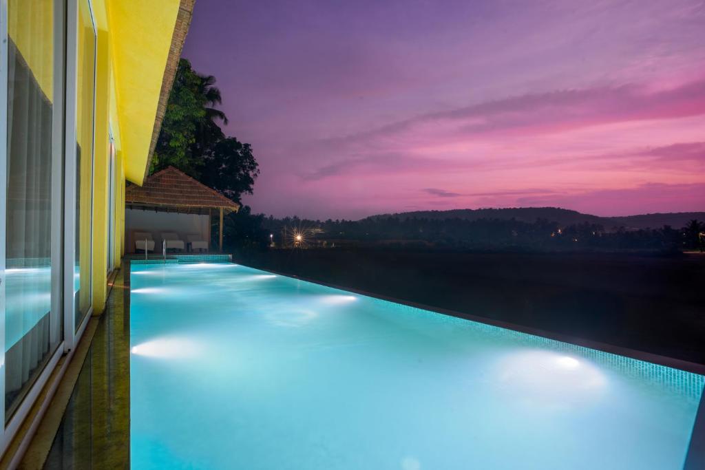 a swimming pool with lights on the side of a building at La Luxo Anjuna in Bardez