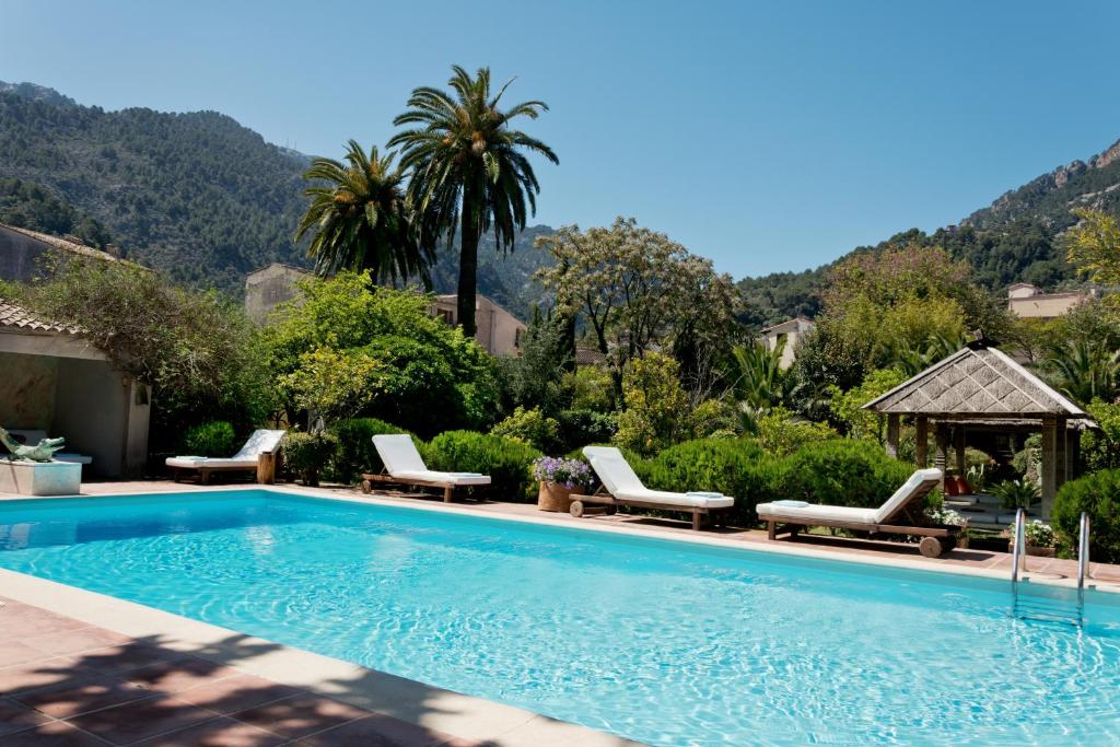 a swimming pool with lounge chairs next to a mountain at Hotel Can Roses in Sóller