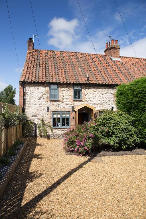 a white brick house with a red roof at No33 THORNHAM BOUTIQUE COTTAGES in Thornham