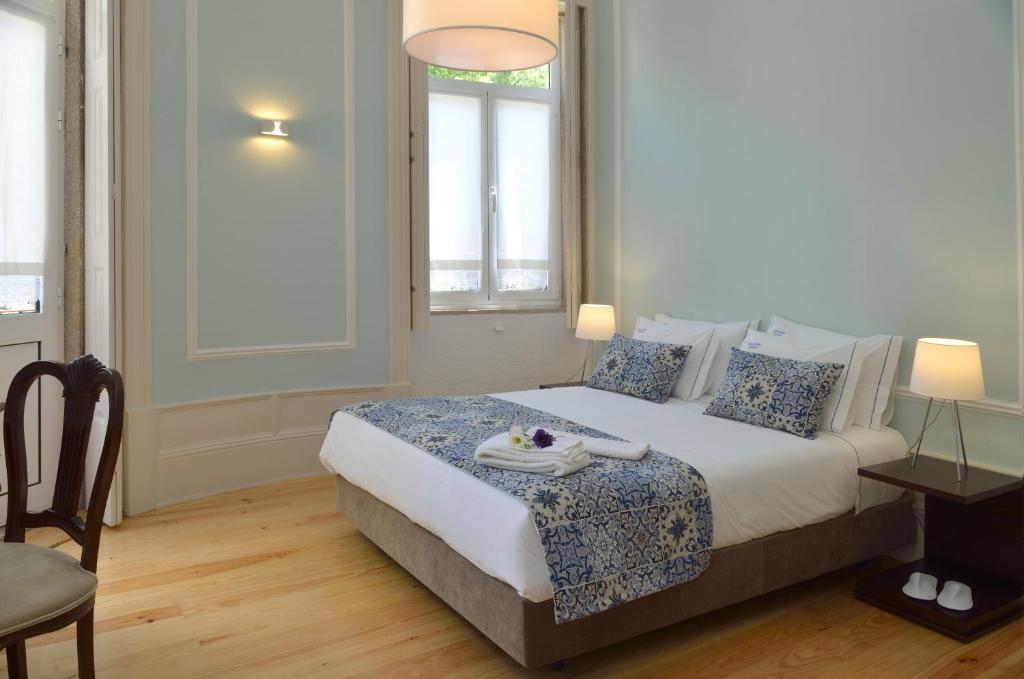 a bedroom with a bed and a chair and a window at Dukes Corner Guest House in Porto