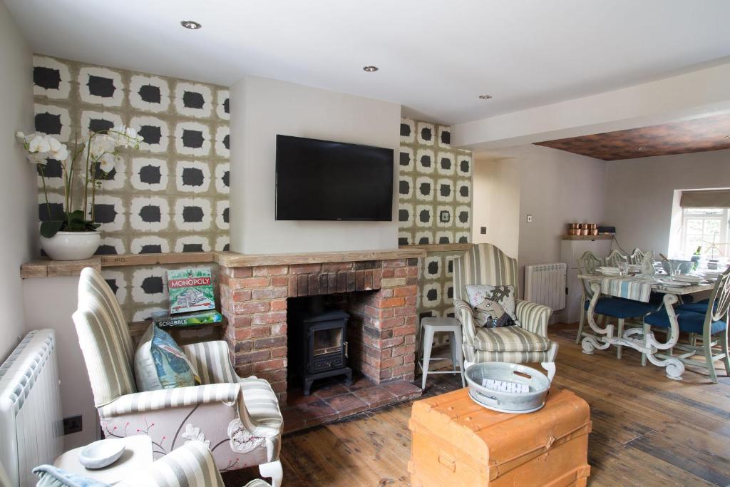 a living room with a fireplace and a tv at No33 THORNHAM BOUTIQUE COTTAGES in Thornham