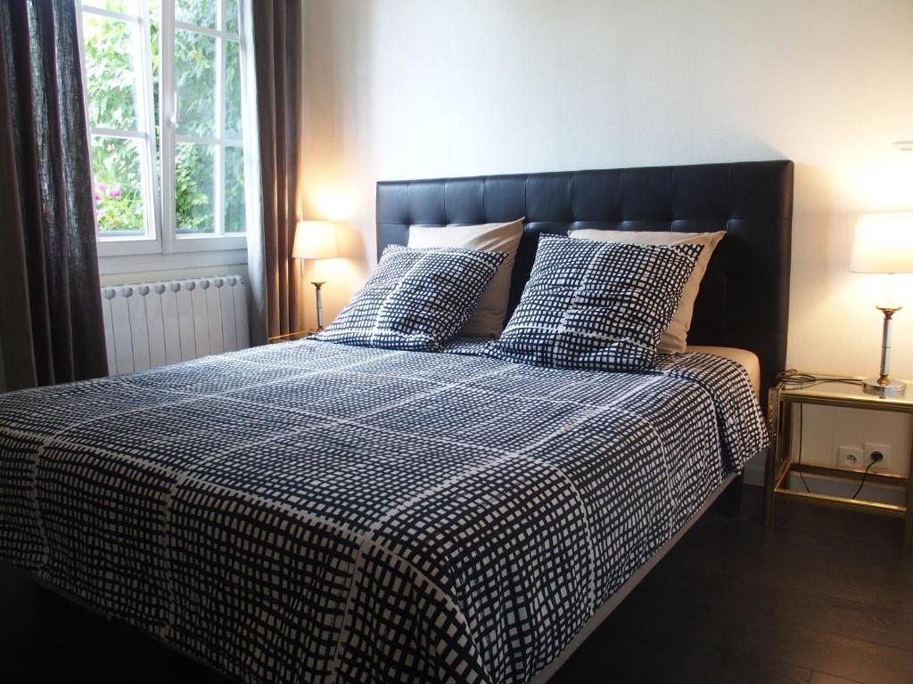 a bed with a blue and white checked comforter and pillows at Bed and Breakfast Le patio in Montigny-lès-Metz