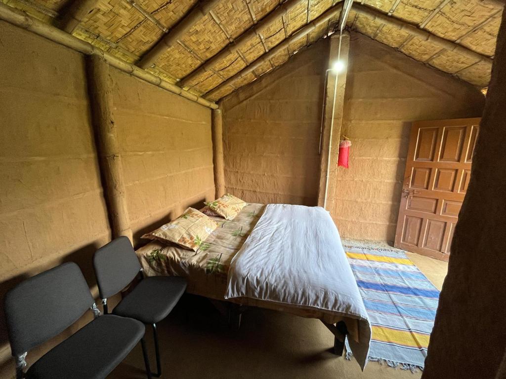 Hameri Homestay- Room 1 في ناينيتال: سرير في غرفة مع كرسيين وباب