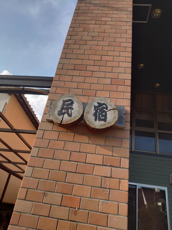 two stone signs on the side of a brick building at 民宿たけだ家 in Saka
