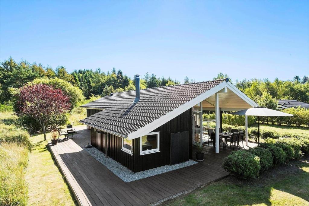 ein schwarzes Haus mit einer Terrasse und einem Regenschirm in der Unterkunft JB403 Fjerritslev - Poppelvej 20 in Fjerritslev