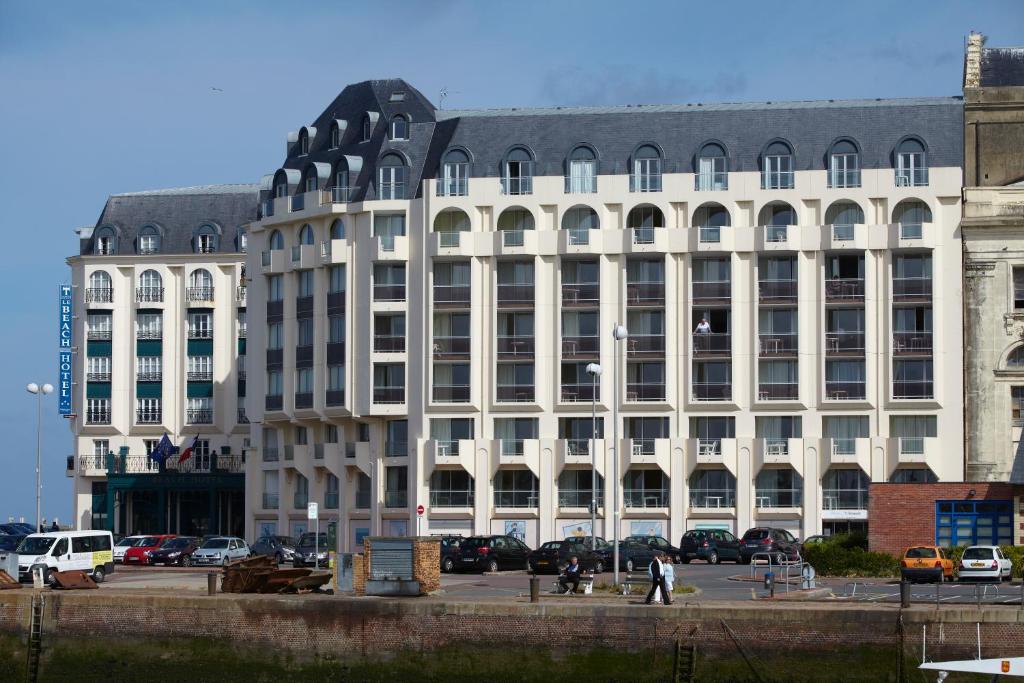 un grand bâtiment blanc avec des voitures garées devant dans l'établissement Residence Le Beach - maeva Home, à Trouville-sur-Mer