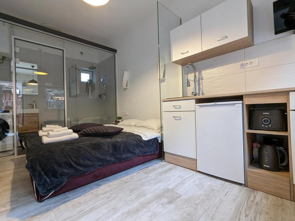 a small kitchen with a bed and a refrigerator at Cowshed w Floor Heating in Ugly Duckling Courtyard in Zagreb