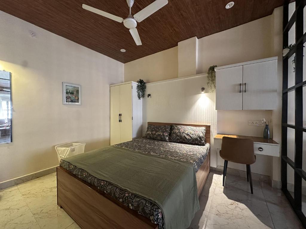 a bedroom with a bed and a desk and a ceiling fan at House of Kashi Homestay- Studio and Budget Rooms in Kashi