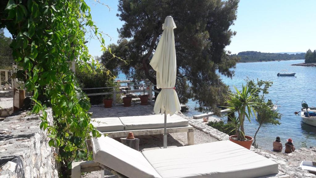 una sombrilla blanca sentada en una playa junto al agua en Holiday Home Villa Venta, en Trogir