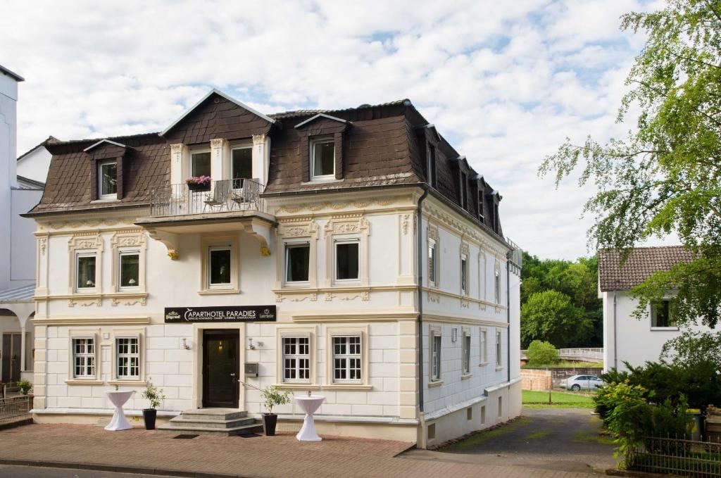un antiguo edificio blanco con techo marrón en Apart Hotel Paradies, en Bad Salzschlirf