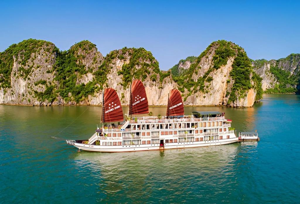 un crucero con velas rojas en el agua en Victory Boutique Cruise, en Ha Long