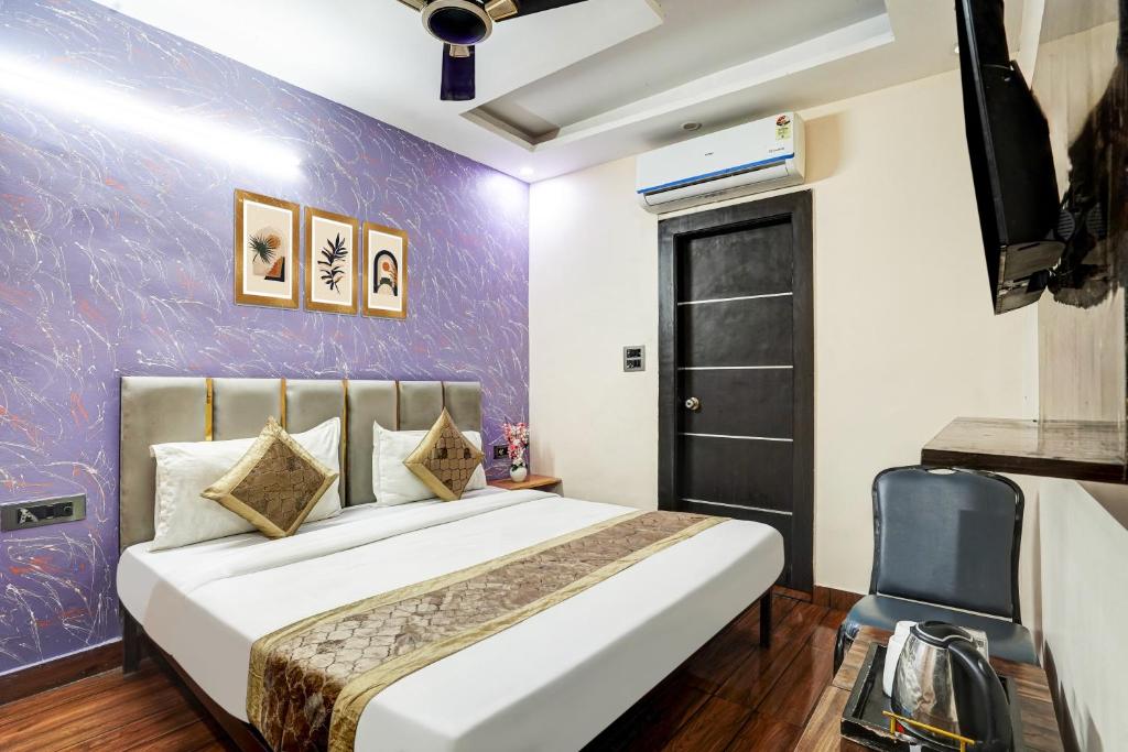 a bedroom with a bed and a purple wall at Hotel Twamev Couple Friendly Laxmi Nagar in New Delhi