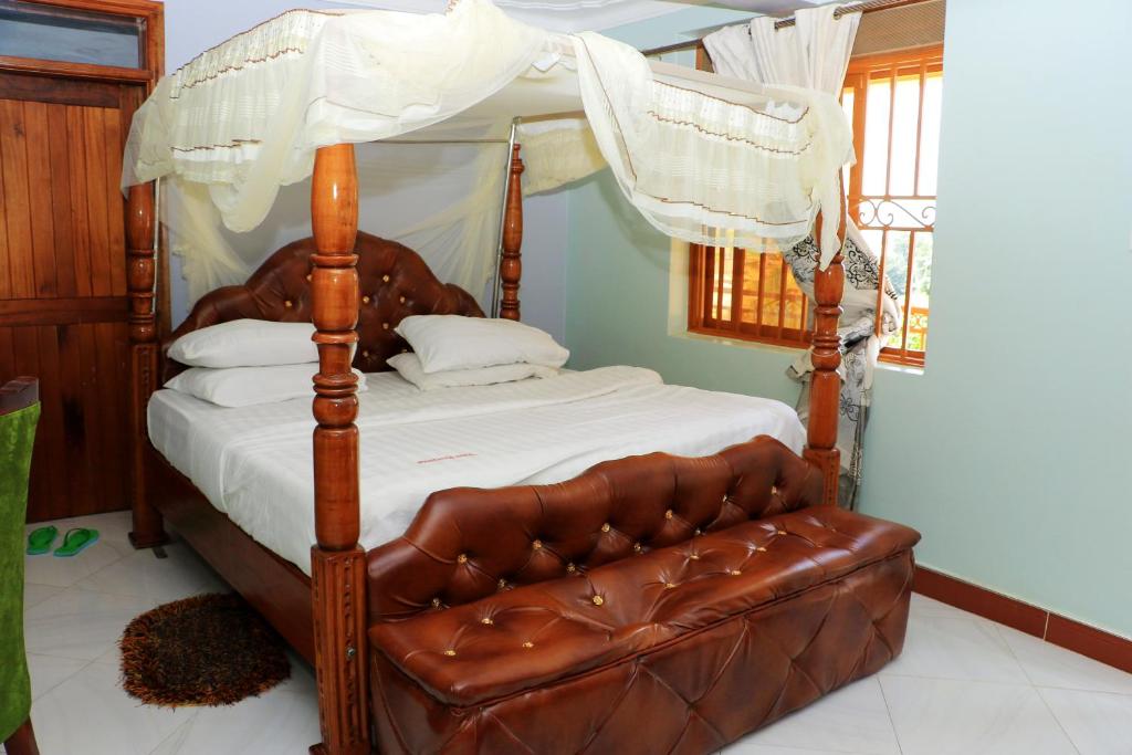 a bedroom with a canopy bed with a leather couch at PrimeRose Hotel Mubende in Mubende