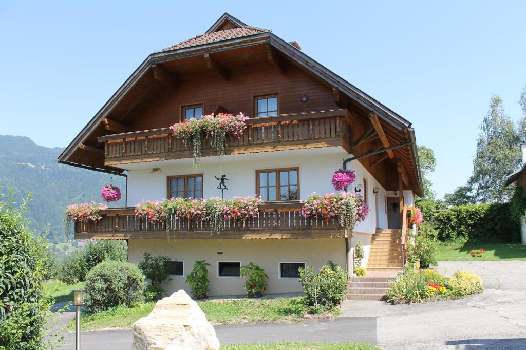 a house with flowers on the balconies on it at Pension Neuhof in Ossiach