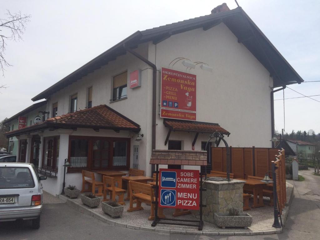 un bâtiment avec des tables et des bancs en bois devant lui dans l'établissement Guest house Okrepčevalnica Zemonska vaga, à Ilirska Bistrica