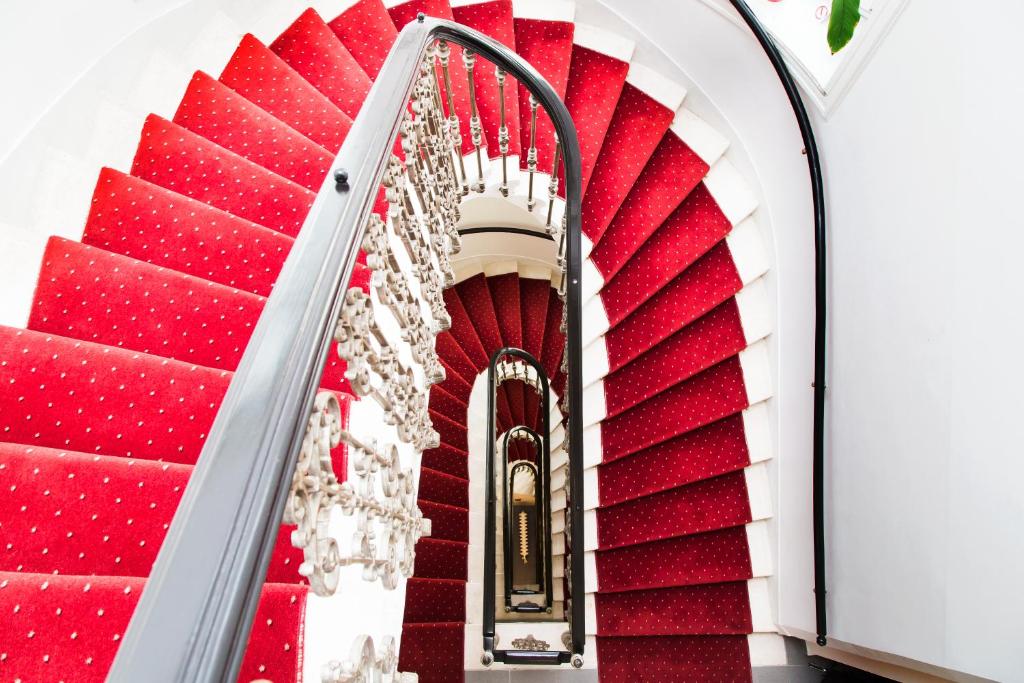 uma escada vermelha e branca com tapete vermelho em Self Check-in Hotel Odeon em Viena
