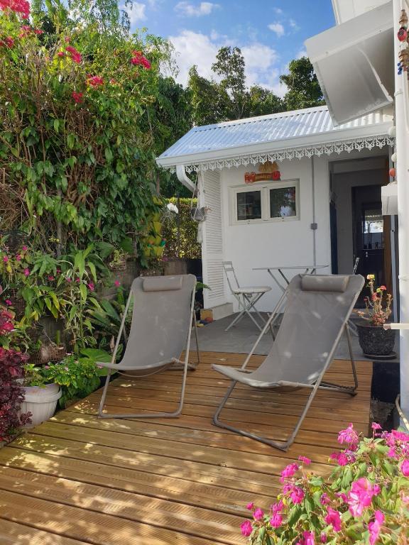 two chairs sitting on a deck in front of a house at Ô Ravenale Manapany Les Bains in Saint-Joseph