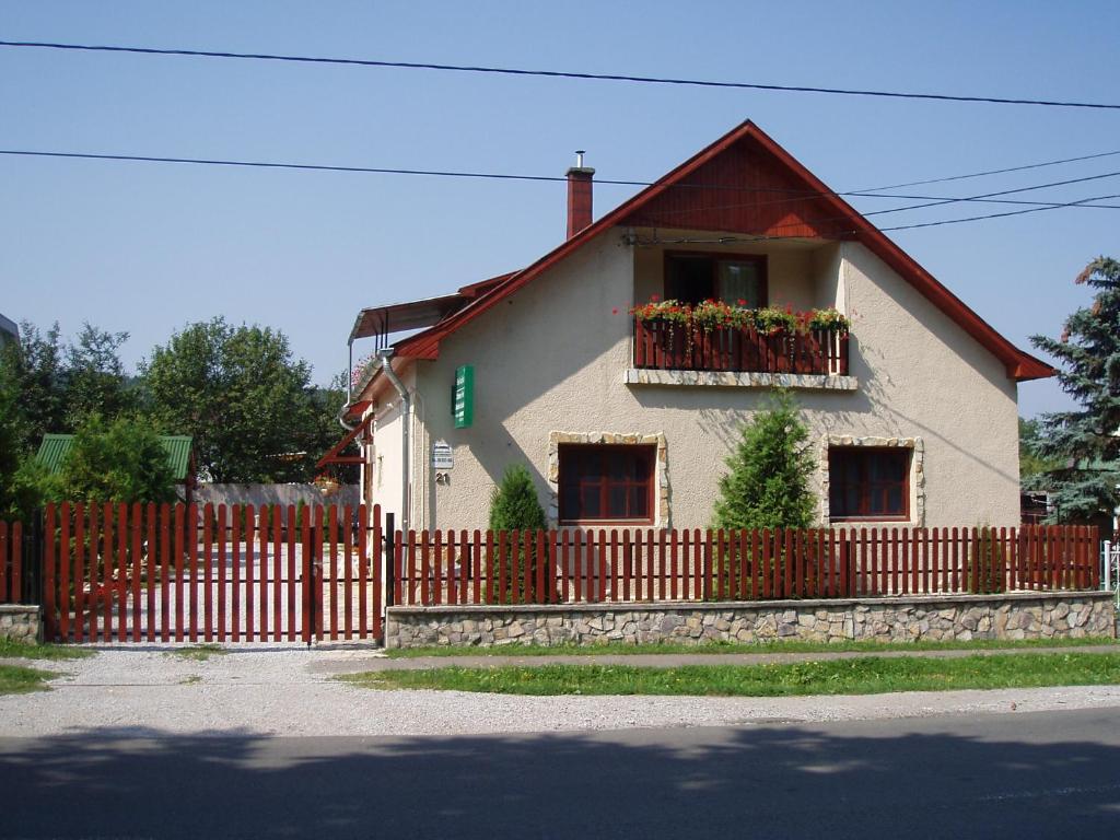 a house with a fence and flowers in a window at Táltos Vendégház in Szilvásvárad