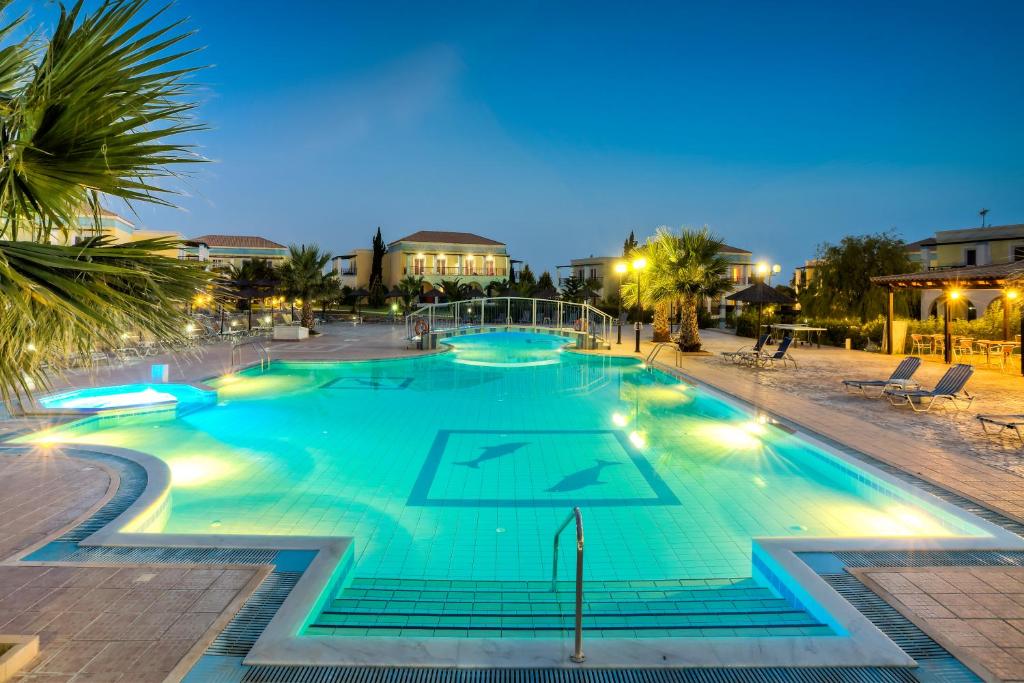 una grande piscina in un resort di notte di Corali Hotel a Tigaki