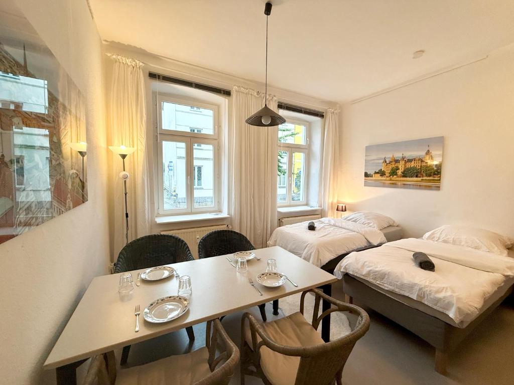 a room with two beds and a table and chairs at Berta - Zentrale Wohnung - 2 Küchenzeilen - Nähe Bahnhof in Schwerin