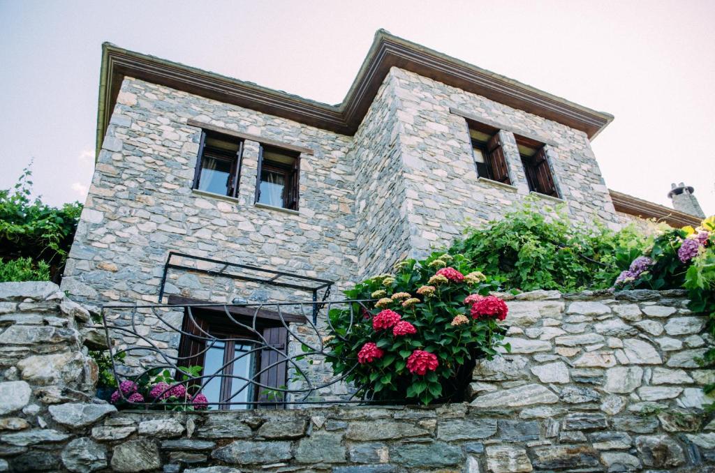 a stone house with flowers on a stone wall at Manolies in Mouresi