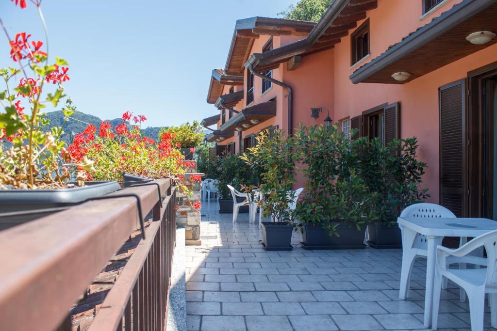 a patio with tables and chairs and potted plants at Hotel Grotto Bagat in Lavena Ponte Tresa