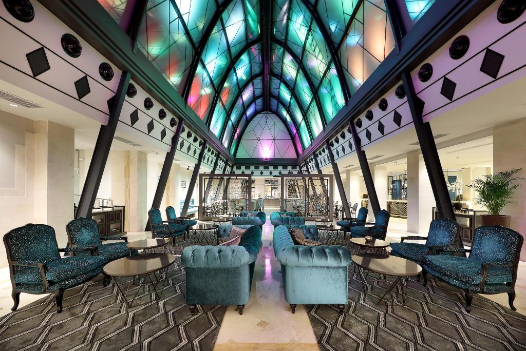 a lobby with chairs and tables and a stained glass ceiling at Eurostars Casa de la Lírica in Madrid
