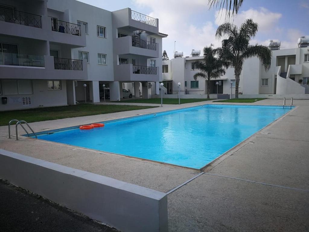 a large blue swimming pool in front of a building at Meneou Apartment in Meneou