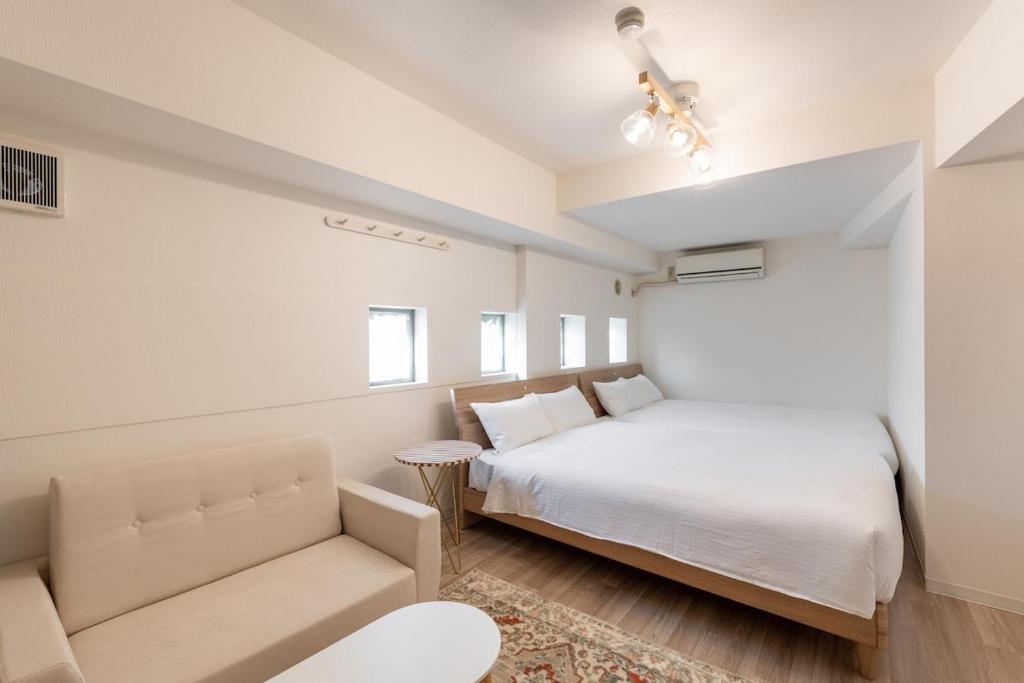 a white bedroom with a bed and a couch at 東新宿1007 Good location within 15 minutes of Shinjuku Station in Tokyo