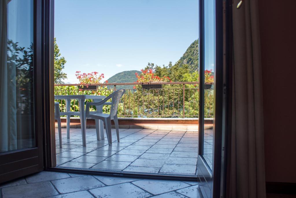 a glass door leading to a balcony with a table at Hotel Grotto Bagat in Lavena Ponte Tresa