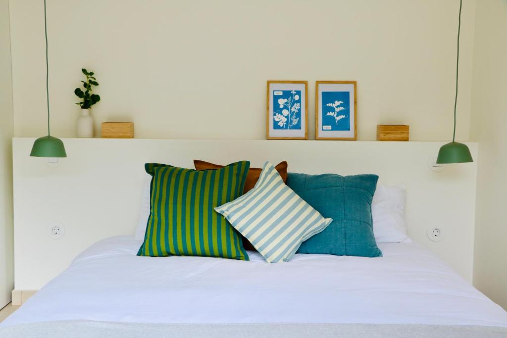 ein weißes Bett mit grünen und blauen Kissen darauf in der Unterkunft Araça Studio - Atlantic Mountain Living in São Vicente