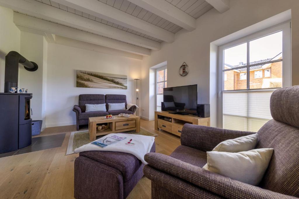 a living room with a couch and a tv at Haus Wind&Wellen, Wohnung Hafen in Wittdün