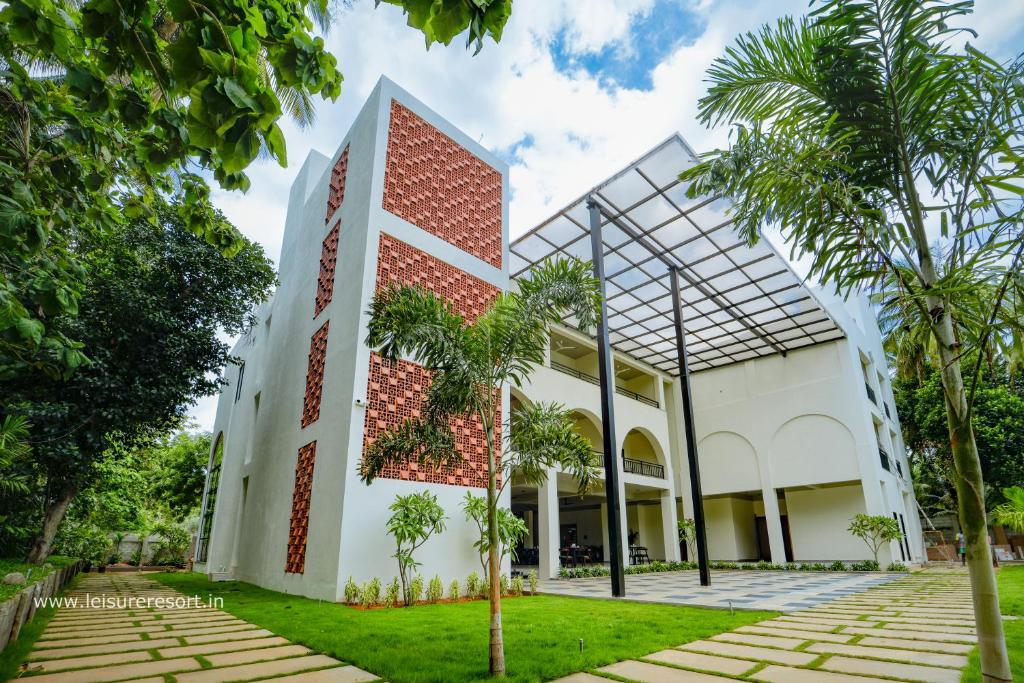 un bâtiment avec un mur de briques et des palmiers dans l'établissement Leisure Resort, à Pondichéry