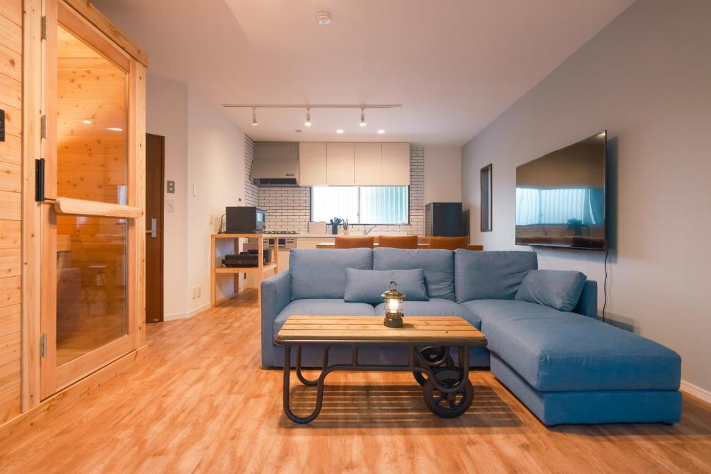 a living room with a blue couch and a table at rinne 九十九里 Beachhouse in Katakai