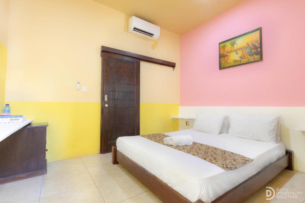 Brown Sugar Homestay في غيلي تراوانغان: غرفة نوم بها سرير في غرفة ذات جدران صفراء ووردية