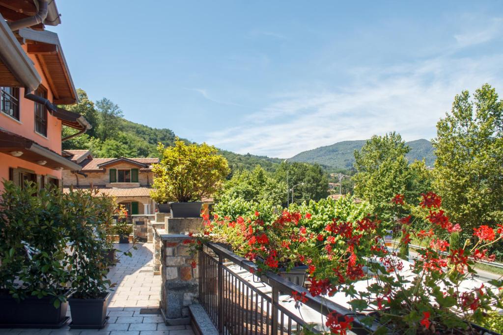 a balcony with red flowers on a house at Hotel Grotto Bagat in Lavena Ponte Tresa