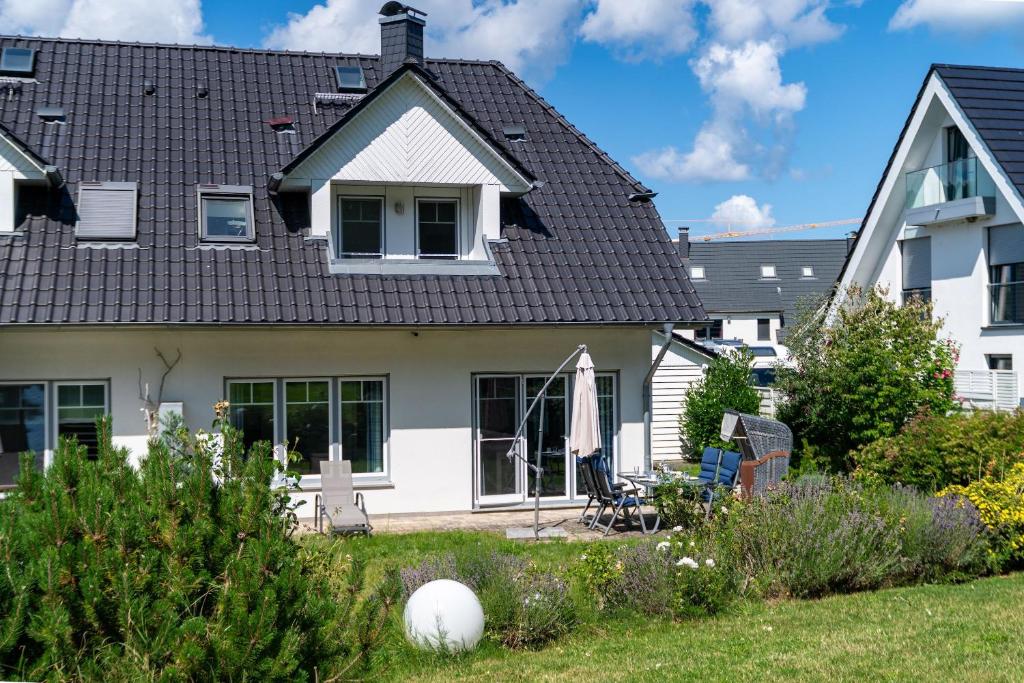 ein weißes Haus mit einem schwarzen Dach in der Unterkunft Ferienhaus "Stella Olivia" in Lobbe