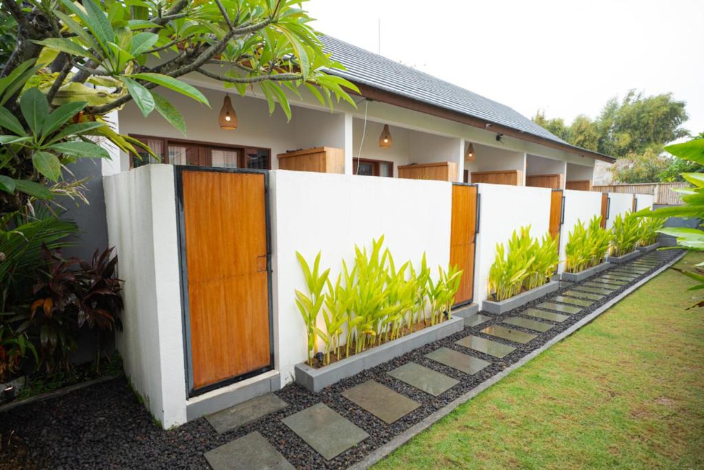 a fence with wooden doors and plants in front of a house at Abimanyu Guest House in Seminyak