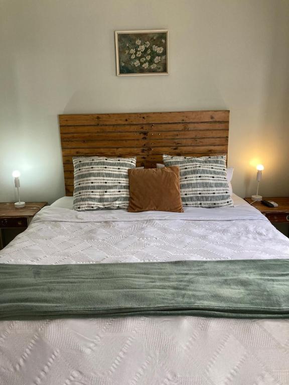 a bed with a wooden headboard and pillows on it at Studio Room Durban North in Durban