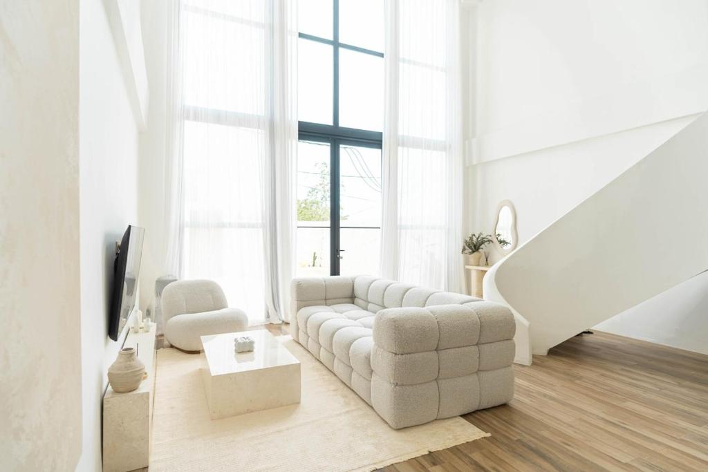 a white living room with a couch and a tv at Casa Uluwatu - Ocean View Villa in Uluwatu