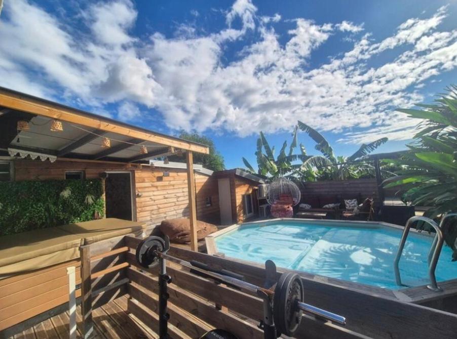a backyard pool with a hot tub and a house at Maison des Ramiers in Saint-Paul