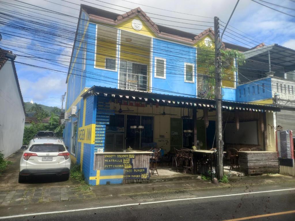 a blue house with a car parked in front of it at Sweden Inn Hostel Chalong in Ban Klang