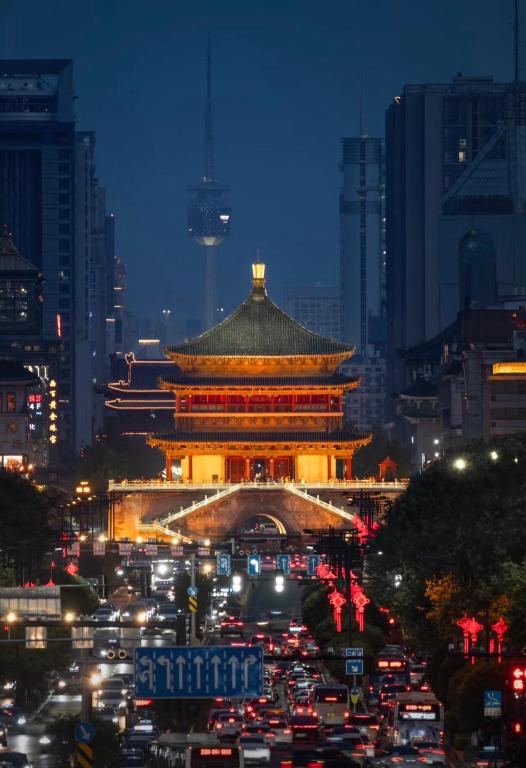 ein chinesisches Gebäude mit Verkehr in einer Stadt bei Nacht in der Unterkunft Xi You Hotel禧又 - near Xi'an City Wall, Daming Palace, with ticket service for featured scenic spots ,Paid Airport shuttle and tour charter services available,Welcome gifts and a cup of freshly ground coffee in Xi'an
