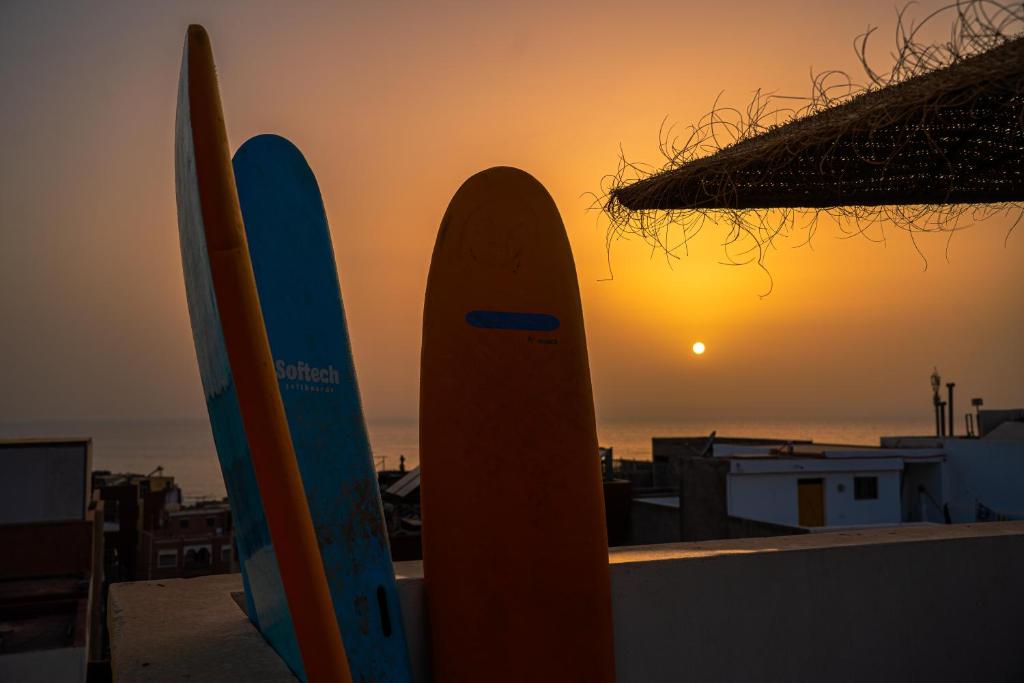 deux planches de surf appuyées contre un mur avec le coucher du soleil dans l'établissement Surf & Sun Apartment in Imsouane, à Imsouane