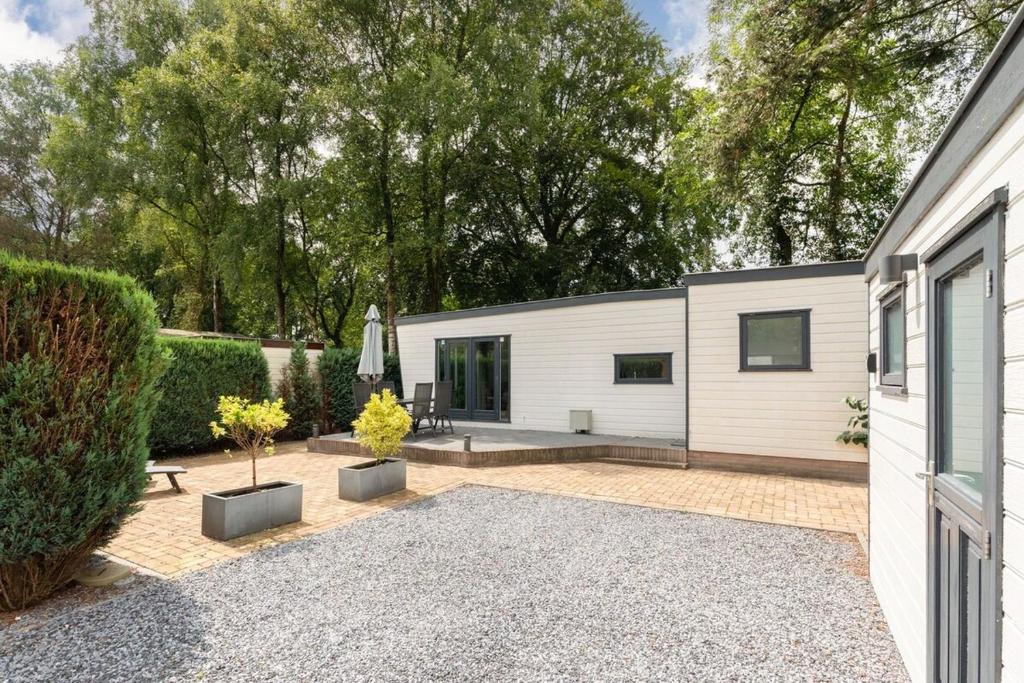 Casa blanca con patio con árboles en Chalet for 4 on the Veluwe, en Putten