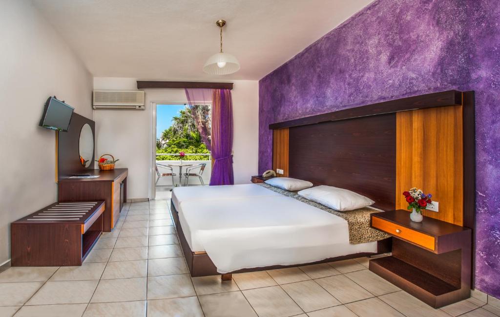 a bedroom with a large bed and a purple wall at Corali Hotel in Tigaki