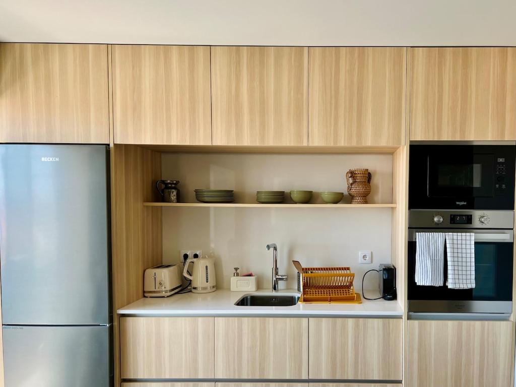a kitchen with a refrigerator and a microwave at Póvoa 3 suites in Póvoa de Varzim